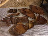 Photo showing all wooden bowls with various shapes, a carved rectangular wooden panel, and the tiki salt and pepper shakers collected on a carpet.