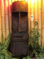 Front view of wooden Tiki carving against bamboo backdrop