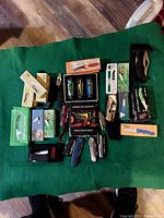 31-piece cutlery collection displayed on green fabric, various boxed and loose knives visible