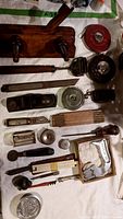 Overview of all tools laid out on a white cloth showing wooden planes, tape measures, hand planes, and measuring devices.