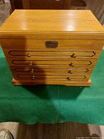 Exterior view of oak jewelry box closed, brass knobs on four front drawers