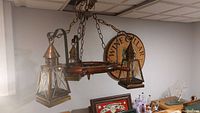 Side view of the nautical chandelier showing three frosted glass lantern lights and wooden ship wheel structure.