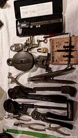 Overview photo showing all 16 tools including digital caliper, pulleys, pipe wrenches, clamps, and padlock.