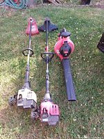 Photo of three outdoor tools placed on grass including two weed wackers and one leaf blower