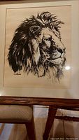 Framed lion print showing detailed lion head portrait in black ink on a light background.