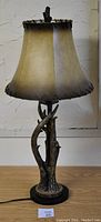 Front view of deer antler lamp showing leather lampshade and lamp base resembling antlers.