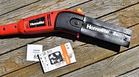 Close-up of the Homelite pole saw housing and included new chain package on wooden deck.