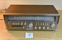 Front view of vintage Lloyd's 8 track tape player and AM/FM stereo receiver with wood grain top and metal front panel, showing control knobs and tuning dial.