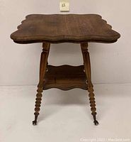 Full front view of the antique Victorian side table showing the carved wood legs with ball and claw feet and the scalloped wooden shelf below the top.