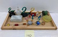 Full view of all the glass trinkets, animals, and paperweights displayed on a wooden tray