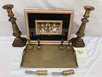 Photo showing the brass tray, butter knives, framed brass tribal figures, and two brass candle sticks
