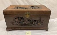 Front side of carved wooden box showing detailed folk art with human figures, pagoda, and landscape