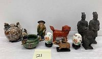Front view of all items including vase with attached figures, pot with seated figure, red Foo Dog, painted eggs, ox figurine, warrior statues, and small animal figurine.