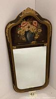 Full view of vintage wooden wall mirror with floral hand painted panel on upper section and mirrored glass below.