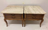Full view of the two square vintage Hekman end tables with natural travertine stone tops and wood bases with drawers.
