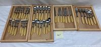 Full view of multiple trays with forks, cutting knives, and spoons featuring pearl handles.