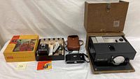 Kodak Cavalcade 520 projector with leather carrying case, Kodak Tourist II camera with case, Kodak Brownie Hawkeye items displayed