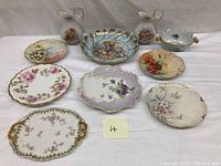 All plates, bowl, and creamers arranged on a white surface showing intricate designs and gold accents.