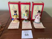 Three Royal Doulton Bunnykins figurines with their original red and cream boxes behind and certificates displayed in front.