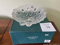 Clear art glass bowl with peacock feather design sitting on a green Maleras Sweden box. The glass is translucent with frosted feather details.