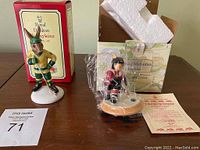 Two Royal Doulton Bunnykins hockey themed figurines displayed on table with their original boxes, one figurine packaged in plastic and one standing free.