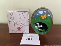 Front view of glass paperweight with original box and auction tag.