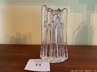 Overall side view of the clear glass candlestick showing vertical elongated teardrop-like shapes in the design and the height of 8 inches.