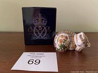 Photo of Royal Crown Derby black box with gold logo and porcelain kitten figurine on a wooden surface with auction label number 69.