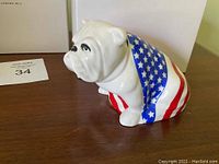 Front-left three-quarter view of white bulldog figurine draped in American flag pattern