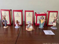 Five Royal Doulton Bunnykins figurines displayed side by side in front of their original boxes on a wooden surface. Each figurine is unique with detailed hand-painted features.