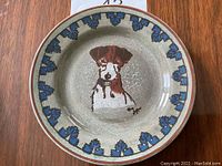 Top view of the decorative plate showing the dog illustration and blue leaf border.
