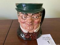 Front view of the Royal Doulton Mr Pickwick Toby Jug featuring the character's face with painted glasses and green hat.