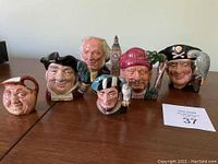 Photo of six Royal Doulton toby jugs arranged on a wooden table showing various character faces including a pirate, a man with a red knit cap, and a man with a parrot on his shoulder.