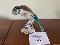 Side view of the signed Royales de Champagnes crystal parrot figurine on a wooden surface.