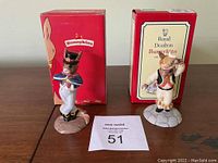 Two Royal Doulton Bunnykins porcelain figurines (Morris Dancer signed and Hornpiper) with their original boxes, displayed upright on a wooden surface with a lot number card in front.