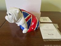 Side view of white glazed ceramic bulldog figurine painted with Union Jack flag design draped over body