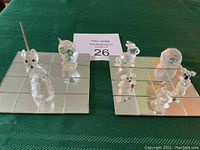 Two mirrored square bases with eight clear crystal animal figurines placed on them representing various animals like owl, mouse, rabbit, hedgehog, and more
