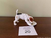 Front side view of the vintage Doulton porcelain dog figurine showing the dog drinking from a bowl on a wooden surface.