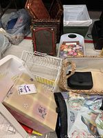 Various plastic baskets, wicker basket, tote basket, fabric items and black item inside beige tote basket