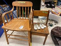 Photo of larger and smaller wooden chairs side by side with vintage baby shoes on smaller chair showing condition and scale