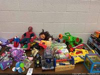 Wide view showing most items in lot including Spider-Man plush, Dora, My Little Pony, troll dolls, water toys and more