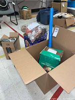 Box containing holiday items including fiber optic bear figure in green box, other decorations, and packaging materials.