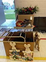 Wide angle showing various Christmas, Easter, and Halloween decorations including brass-look wall rack, decorative basket, wooden Easter bunnies, and Santa on reindeer figure.