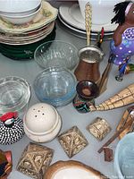 Various kitchenware including plates, glass bowls, shakers, small ceramic jars and animal figurines displayed on a table.