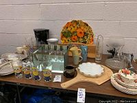 Overview of assorted glassware and mugs including Minions glasses, Tom and Jerry mugs, floral serving trays, and a moose motif candle holder and pitcher