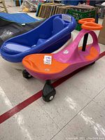 Photo showing pink and orange plasma scooter with black wheels alongside two blue plastic infant tubs.