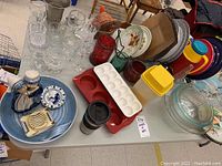 Overview of table with all items including glassware, silicone trays, Tupperware, ceramic plates, and colored glass jars.