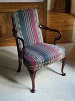 View of the full chair showing striped fabric upholstery, cabriole legs, and open arms with nailhead trim detailing