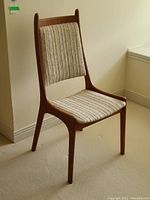 Side view of the mid-century teak side chair showing the wooden frame and textured upholstery on the seat and back.