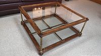 Full top view of square wood frame coffee table with bevelled glass top and brass trim